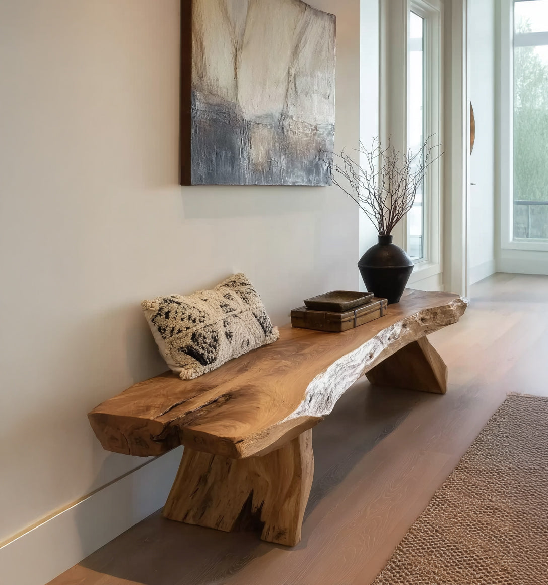 Natural live edge wood bench with decorative pillow, books, and black vase in modern hallway